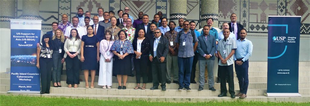 Participants from Fiji, Republic of Marshall Islands, Nauru, Palau, Papua New Guinea, Tuvalu, and Vanuatu, USAID and US-SEGA, Taiwan ICDF, and USP gather in front of USP’s pillars and wall murals representing all 12 Pacific Island Countries. 