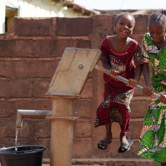children in rural village using a water pump
