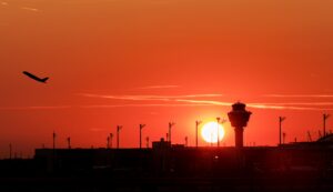 airport terminal at sunset with plane taking off in the background