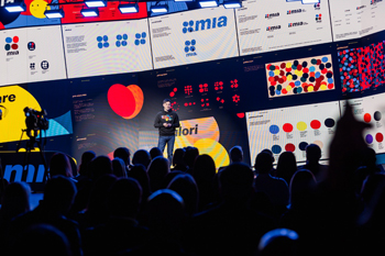 A person standing on a stage with a large screen with a crowd watching, for the USAID MISRA launch event for the MIA Instant Payment System. April 2024, Chisinau, Moldova